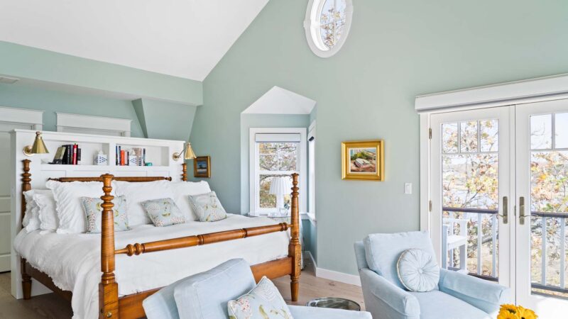 Light blue bedroom, two armchairs, sunflowers, big windows, balcony view – McPhee Associates of Cape Cod.